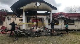 Aparat memasang garis polisi di lokasi terbakarnya Kantor KPU Distrik Dekai, Kabupaten Yahukimo, Papua Pegunungan, Minggu (6/8/2023).