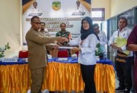 Kepala Distrik Mimika Barat, Christian P. Warinussy, menyerahkan usulan program-program kepada Tim Asistensi Bappeda Kabupaten Mimika, dalam hal ini Koordinator Musrenbang Distrik Mimika Barat, Musryah. (Foto: Galeri Papua/Endy Langobelen)