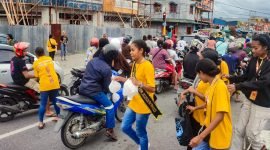 Duta TIFA 2023, Ocean Nussi, bersama rekan-rekannya dari Tifa Creative melaksanakan program Suara Tifa dengan membagikan ratusan bingkisan kepada para pengendara di perempatan lampu merah Pasar Lama, Timika, Papua Tengah, Jumat (12/7/2024) sore. (Foto: Galeri Papua/Endy Langobelen)