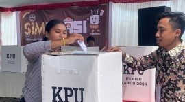 Seorang warga setelah mencoblos hendak memasukkan surat suara ke dalam kotak suara. (Foto: Galeri Papua/Wahyu)