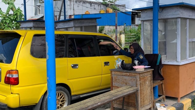 Petugas retribusi Disperindag Kabupaten Mimika sedang melayani seorang pengemudi saat akan bergegas meninggalkan portal keluar di Pasar Sentral Timika. (Foto: Galeri Papua/Ahmad)