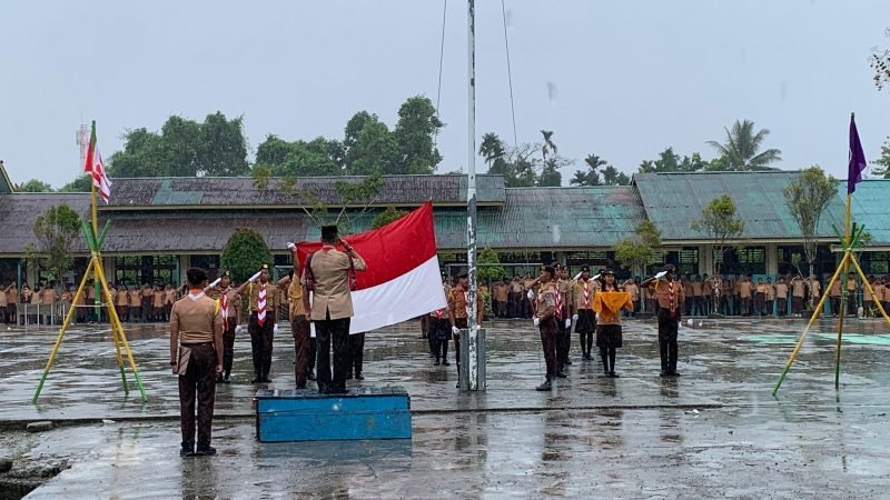 Momen pengibaran bendera pusaka dalam upacara peringatan HUT Pramuka ke-64 tahun di SMA Negeri 1 Mimika di bawa derasnya hujan, bertempat di lapangan sekolah, Kamis (14/8/2025). (Foto: Galeri Papua/Ahmad)