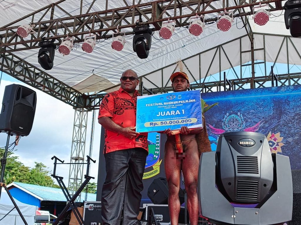 Gubernur Papua Tengah, Meki Nawipa, menyerahkan hadiah kepada Kabupaten Dogiyai selaku juara I pada Festival Budaya Pelajar Papua Tengah 2025 di Nabire. (Foto: Istimewa)