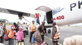 Karyawan dan keluarga tiba di Bandar Udara Enarotali di Kabupaten Paniai sedang mengeluarkan bagasi dari Pesawat Twin Otter. (Foto: Istimewa/Dokumen PTFI)