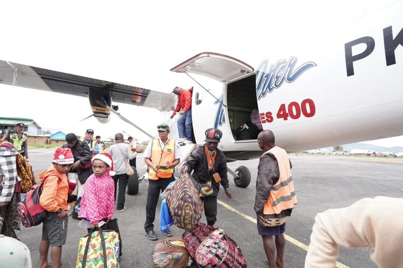 Karyawan dan keluarga tiba di Bandar Udara Enarotali di Kabupaten Paniai sedang mengeluarkan bagasi dari Pesawat Twin Otter. (Foto: Istimewa/Dokumen PTFI)