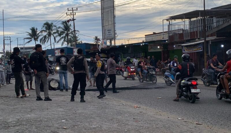 Aparat kepolisian membersihkan arang ban yang dibakar oleh para pendulang di Jalan Leo Mamiri Timika, Selasa (17/2/2026). (Foto: Galeri Papua/Ahmad)