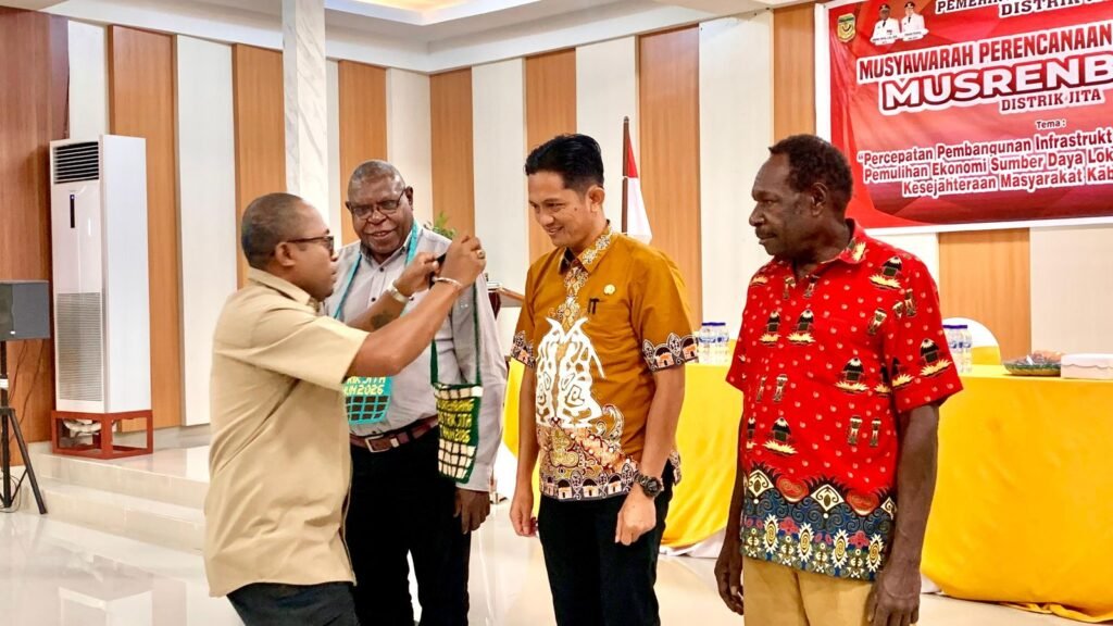 Kepala Distrik Jita, Suto Rontini, mengalungkan cendera mata kepada tim pendamping dari Bappeda Kabupaten Mimika pada seremoni pembukaan Musrembang tingkat distrik 2026. (Foto: Galeri Papua/Ahmad)