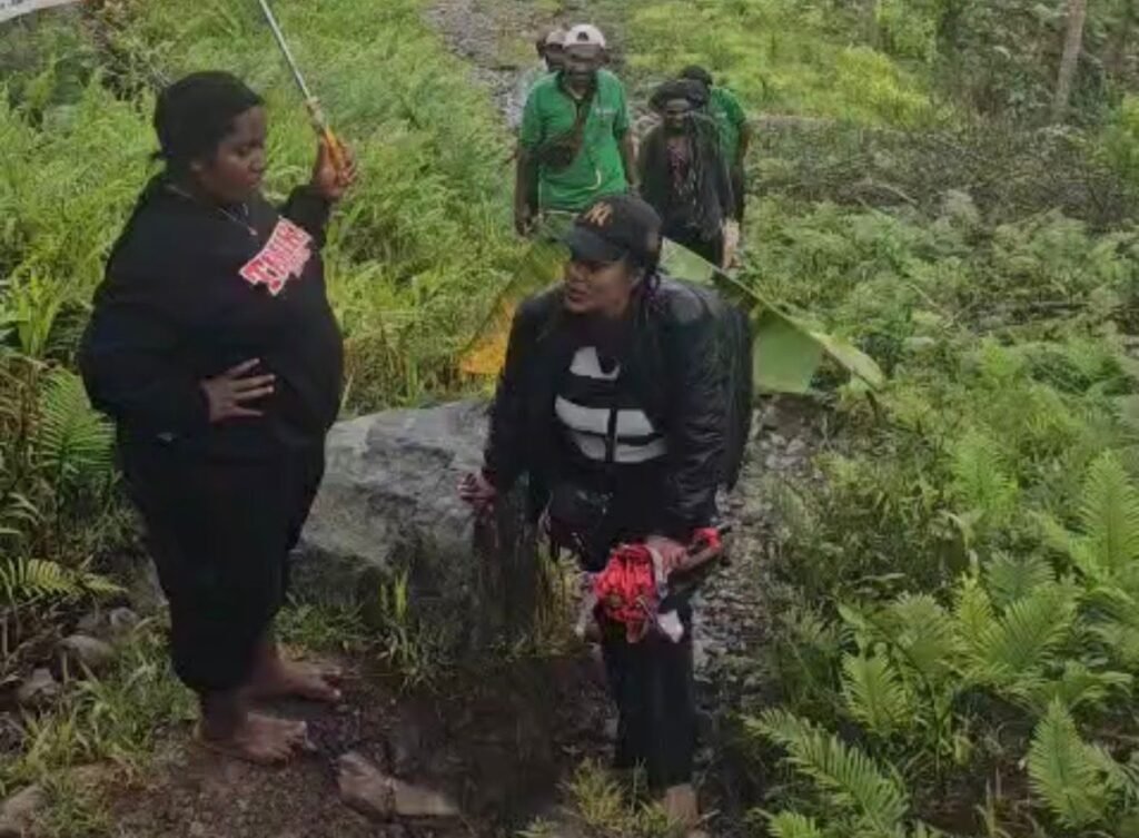 Tenaga kesehatan berjalan kaki di bawah guyuran hujan untuk memberikan pelayanan kepada masyarakat di Distrik Tembagapura, Mimika. (Foto: Dok. Puskesmas Aroanop)