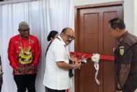 Kajati Papua, Dr. Jefferdian, melakukan pengguntingan pita sebagai tanda diresmikannya dua unit rumah Kejari Mimika yang merupakan hibah dari Pemkab Mimika senilai Rp1,5 miliar, Sabtu (18/4/2026). (Foto: Galeri Papua/Endy Langobelen)