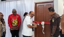 Kajati Papua, Dr. Jefferdian, melakukan pengguntingan pita sebagai tanda diresmikannya dua unit rumah Kejari Mimika yang merupakan hibah dari Pemkab Mimika senilai Rp1,5 miliar, Sabtu (18/4/2026). (Foto: Galeri Papua/Endy Langobelen)