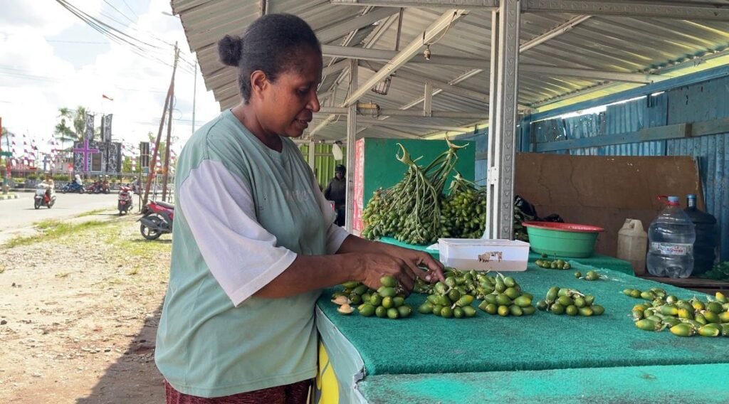 Ira Imelda Apoka, pedagang pinang asal Suku Kamoro, menata dagangannya. (Foto: Galeri Papua/Endy Langobelen)