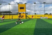  (Jersey kuning hijau) seorang pemain SMANSA sedang menguasai bola dan hendak menyerang pertahanan SMAN 4 Mimika dalam lanjutan turnamen Mini Soccer Kapolda Cup II. Bertanding di Goldstone Arena, Jumat (15/5/2026). (Foto: Galeri Papua/Ahmad)