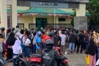 Ratusan orang tua dan siswa yang berdiri mengantre menunggu giliran di depan pagar SMANSA Mimika, Senin (22/6/2026). (Foto: Galeri Papua/Ahmad)
