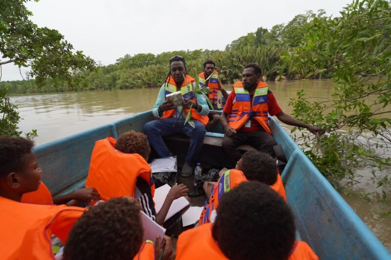 David Nataime seorang Pemandu Tour Ekowisata Mangrove Pigapi Sedang menjelaskan manfaat Tumbuhan Ndoa atau dalam bahasa indonesia disebut Jeruju (Acanthus ilicifolius) yang digunakan sebagai bahan baku utama Minuman Ndoa kepada murid dan guru SD Negeri Pigapu. (Foto: Istimewa)