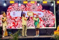 Ketua Tim Wilayah Indonesia Timur untuk Event Daerah Kementerian Pariwisata RI, Joko Suharbowo, menyerahkan sertifikat KEN kepada Ketua Umum Tifa Creative, Dina Merani, pada malam kedua penyelenggaraan TIFA 2026 di pelataran Graha Eme Neme Yauware, Timika, Jumat (3/7/2026). (Foto: Galeri Papua/Endy Langobelen)