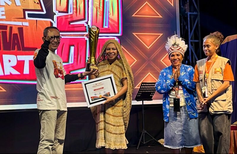 Ketua Dekranasda Kabupaten Deiyai yang juga Ketua TP-PKK Deiyai, Fransina Rumbiak Mote, menerima piagam dan piala juara umum TIFA 2026 yang diserahkan oleh Joko Suharbowo selaku Ketua Tim Wilayah Indonesia Timur untuk Event Daerah pada Kementerian Pariwisata RI. (Foto: Galeri Papua/Endy Langobelen)