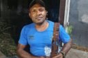 Simson Samin memegang patung yang merupakan hasil pahatannya. (Foto: Galeri Papua/Kevin Kurni)