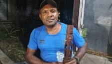 Simson Samin memegang patung yang merupakan hasil pahatannya. (Foto: Galeri Papua/Kevin Kurni)