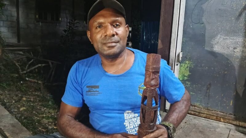 Simson Samin memegang patung yang merupakan hasil pahatannya. (Foto: Galeri Papua/Kevin Kurni)