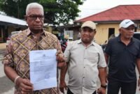 Bupati Mimika, Johannes Rettob, memperlihatkan surat laporan polisi yang ditujukan kepada Media Papua News Online. (Foto: Istimewa/Evan)