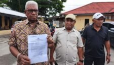 Bupati Mimika, Johannes Rettob, memperlihatkan surat laporan polisi yang ditujukan kepada Media Papua News Online. (Foto: Istimewa/Evan)