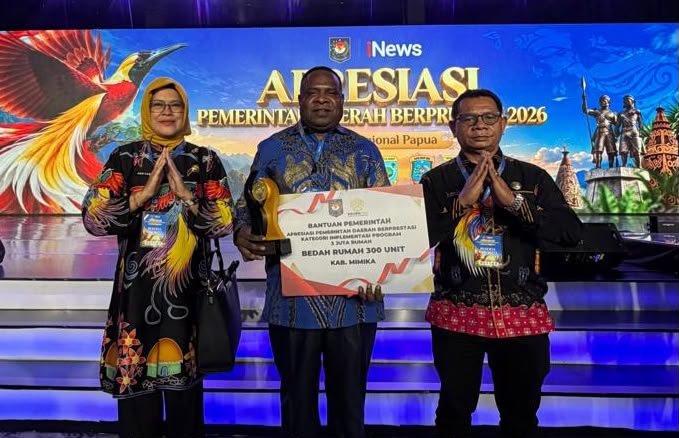 Pj Sekda Mimika Abraham Kateyau memegang penghargaan didampingi dua pejabat eselon di lingkungan Pemkab Mimika. (Foto: Pemkab Mimika)