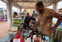 Alexander Giban saat ditemui pelataran Graha Eme Neme Yauware, sedang melayani customer di stan kopi miliknya pada Festival dan Bazar UMKM 2026. (Foto: Galeri Papua/Endy Langobelen)