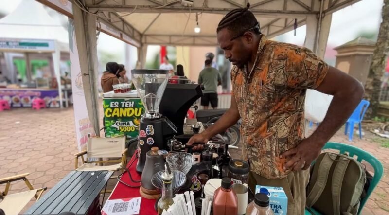 Alexander Giban saat ditemui pelataran Graha Eme Neme Yauware, sedang melayani customer di stan kopi miliknya pada Festival dan Bazar UMKM 2026. (Foto: Galeri Papua/Endy Langobelen)