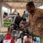 Alexander Giban saat ditemui pelataran Graha Eme Neme Yauware, sedang melayani customer di stan kopi miliknya pada Festival dan Bazar UMKM 2026. (Foto: Galeri Papua/Endy Langobelen)