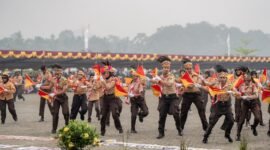 Penampilan tarian anak-anak pramuka saka bhayangkara dalam kegiatan upacara HUT ke-30 Kabupaten Mimika di halaman Kantor Pusat Pemerintahan, Jalan Poros SP3, Timika, Papua Tengah, Senin (12/10/2026). Langit tampak kabut berasap akibat kebakaran hutan di sejumlah daerah di Papua. (Foto: Galeri Papua/Fernando Rio)