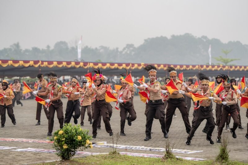 Penampilan tarian anak-anak pramuka saka bhayangkara dalam kegiatan upacara HUT ke-30 Kabupaten Mimika di halaman Kantor Pusat Pemerintahan, Jalan Poros SP3, Timika, Papua Tengah, Senin (12/10/2026). Langit tampak kabut berasap akibat kebakaran hutan di sejumlah daerah di Papua. (Foto: Galeri Papua/Fernando Rio)